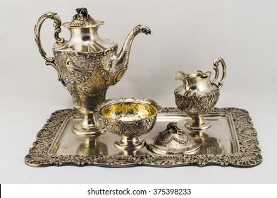 Silver coffee set. Silver sugar bowl, coffee pot, a jug of milk. They stand on a silver platter. 