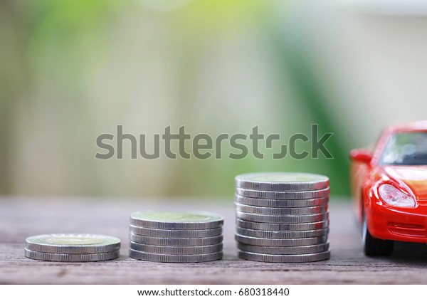 Silver coin of\
pile with red car model in concept savings to buy a new car or\
value of car and journey\
insurance.