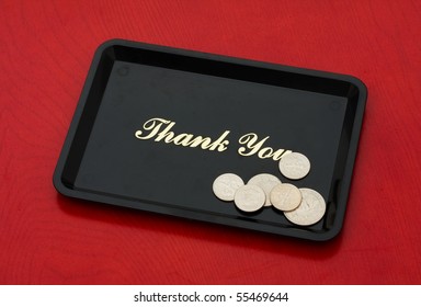 Silver coins on a black tray on a wood background, tip money