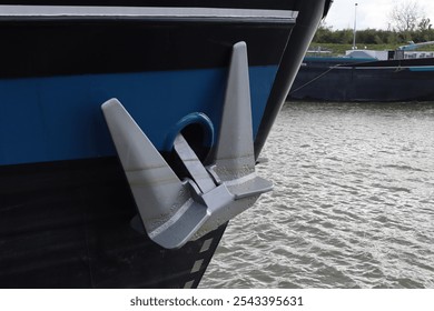 Silver colored anchor hangs on the side of a boat or ship