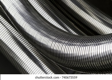 Silver colored metal hoses as grooved tubes. Flexible connector.