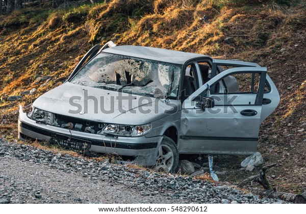 Silver\
colored stolen car that have been crashed and ditched on the side\
of a dirt road. Totally vandalized and\
wrecked.