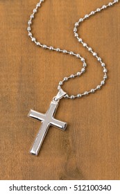 Silver Cross With Necklace On Wooden Background