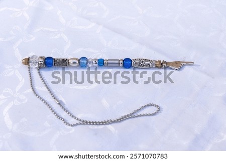 A silver, decorative, beaded yad, a pointer used to assist a Torah reader follow the Hebrew text when reading from a Torah scroll. 