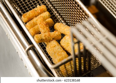 A Silver Deep Pan Industrial Kitchen Oil Fryer, With Golden Oil, Bubbling And Frying Potatoes