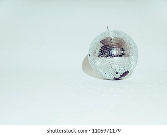 Silver disco ball on a white background. Light reflects on the floor.
