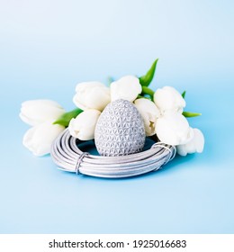 Silver easter egg in the nest and white tulips