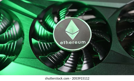 Silver Ethereum coin lies on a black video card iilluminated by green light . Crypto currency. - Shutterstock ID 2053915112