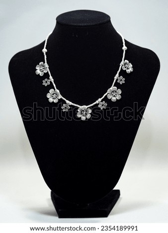Silver flower necklace on black mannequin