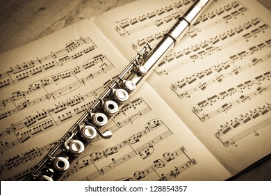 Silver Flute On An Ancient Music Score Background