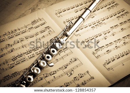 Silver flute on an ancient music score background