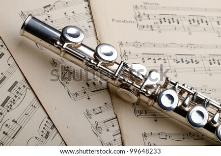 Silver flute on an old musical background