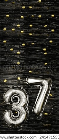 Silver foil balloon number 37 on a background of black tinsel with gold confetti. Birthday card, inscription thirty-seventh. Anniversary event. Vertical banner. copy space.