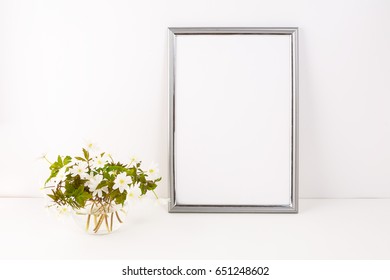 Silver frame mockup with blooming Rue Anemone. Empty frame mock up for presentation artwork. Template framing for modern art.