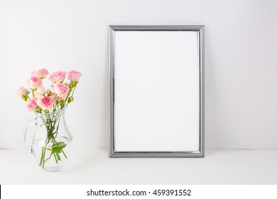Der silberne Rahmen ist mit rosafarbenen Rosen bespannt. Porträt oder Plakat leere weiße Rahmen Vorlage für Präsentationen.