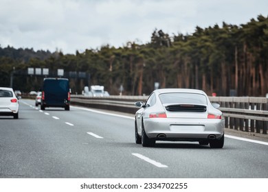 Silver German roadster coupe on the highway. Silver sport coupe. Expensive sports car rushing along the highway - Shutterstock ID 2334702255