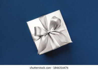 Silver Gift Box With Bow On Blue Background. Flat Lay, Top View.