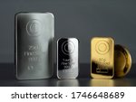 Silver and gold bars and coin on a dark background.