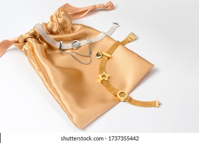 Silver And Gold Bracelets In Golden Silk Gift Bag, Jewelry Flatlay On Neutral Background. Top View Of Fashion Luxury Woman Accessories, Jewelry And Shopping Concept. Trendy Flat Lay Composition.