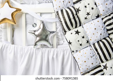 Silver And Gold Star Shaped Pillows And Patchwork Comforter On A White Baby Cot Close Up