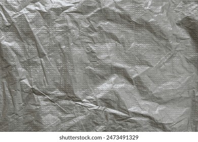 Silver gray plastic film with embossed dots background. Wrinkled gray film texture. Grunge backdrop.