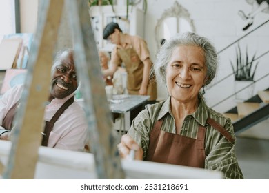 Silver haired woman smiling widely while enjoying drawing process, her African American husband looking at her painting - Powered by Shutterstock