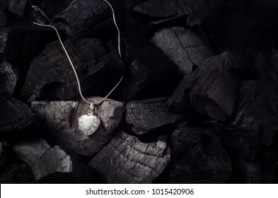 Silver heart shape locket with necklace on black charcoal texture background