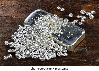 silver ingot and granules on wooden background
