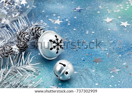 silver jingle bells with christmas tree branches and decoration on blue background closeup view