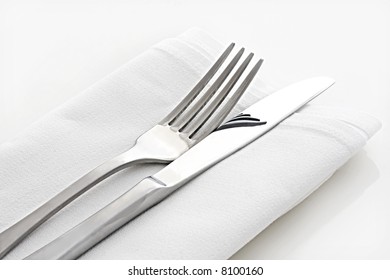 Silver Knife And Fork On White Linen Napkin.