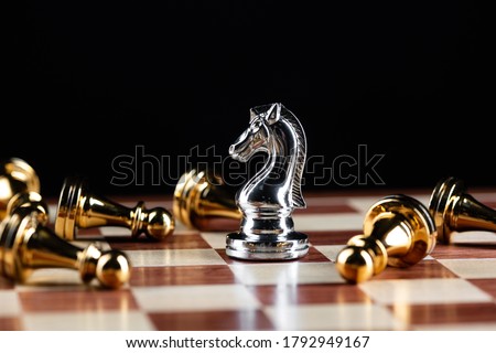 Silver knight chess defeats gold pawns on wooden chessboard. Intellectual duel and tactical battle in business. Strategy planning, leadership and teamwork. Checkmate and winning in game concept.