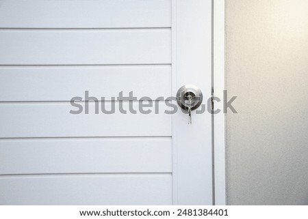 Silver knobs and keys on white modern wooden doors against the gray concrete background for forgot to close the door or lost the key and safety with security concept.