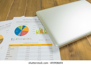 silver laptop and chart document on wooden background