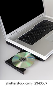 Silver laptop computer with CD tray opened.