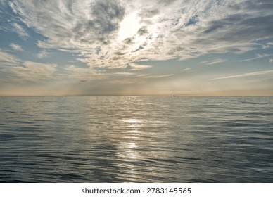 Silver light breaks through dramatic clouds onto the calm surface of the Tyrrhenian Sea near Viareggio, Italy, creating a magical seascape.