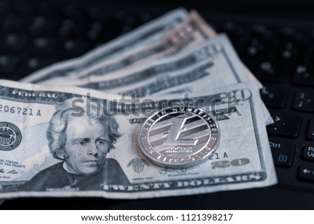Silver Litecoin Cryptocurrency Token On US Currency and Computer Keyboard 