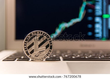Silver Litecoin on keyboard of notebook with chart