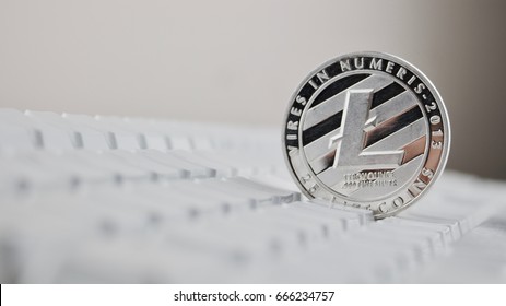 Silver Litecoin physical cryptocurrency coin on white commputer keyboard.