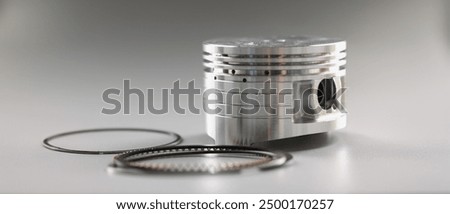 Silver mechanical round part of the engine piston on a gray background, close-up. New shiny auto detail, repair