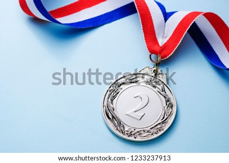 Silver medal 2 place with ribbon on a light blue background, the concept of victory or success