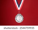 Silver medal with striped ribbon on red background