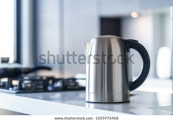 Silver metal electric kettle for boiling water and\
making tea on a table in the kitchen interior. Household kitchen\
appliances for makes hot\
drinks
