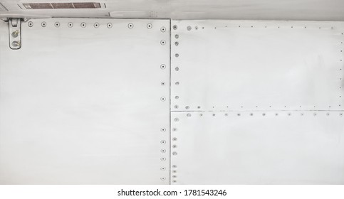Silver Metal Surface Of The Aircraft Fuselage With Rivets. Fuselage Detail View. Airplane Metallic Fuselage Detail With Rivets.