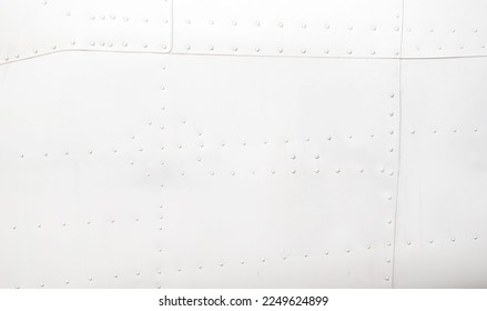 Silver metal surface of the aircraft fuselage with rivets. Fuselage detail view. Airplane metallic fuselage detail with rivets.