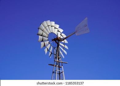 Silver Metallic Farm Water Pump Windmill Against Deep Blue Sky Over African Water Borehole At Okonjima Nature Reserve, Namibia, Africa.                    