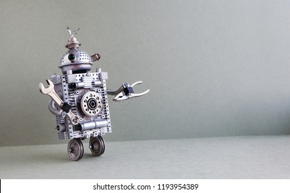 silberner Metallroboter auf grauem Hintergrund. Zwei Räder inländischen Servant Roboter Charakter mit Hand-Schraubenschlüssel. Kreatives Design Steampunkspielzeug, Kopienraum.