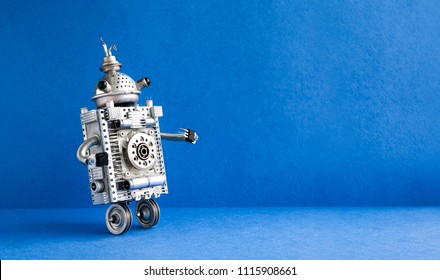 Silver Metallic Robot On Blue Background. Two Wheels Domestic Servant Robotic Character With Antenna. Creative Design Steampunk Toy, Copy Space