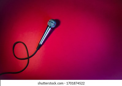 Silver Microphone On A Red Background, With A Black Cord.