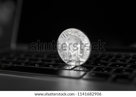 Silver Monero coin on a laptop keyboard. Exchange, bussiness, commercial. Profit from mining crypt currencies. Miner with ethereum coin.