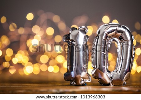 Silver number 10 celebration foil balloon against blurred light background